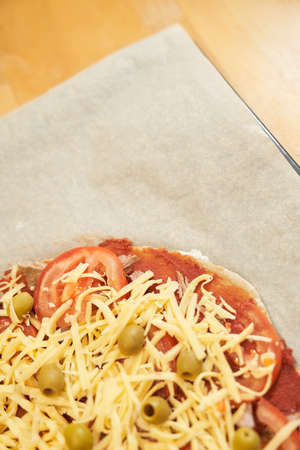Pizza with beef on baking paper prepared for baking. Healthy gluten-free pizza on wooden table. Gluten-free cooking class. Photo with copy space.の写真素材