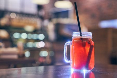 Christmas drink red non-alcoholic mulled wine with a straw on the background of the cafe interior,...