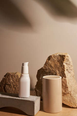 White ceramic opaque bottle on a beige background without labels on natural podium, stones and podium for your product demonstration with tropical plant frameの写真素材