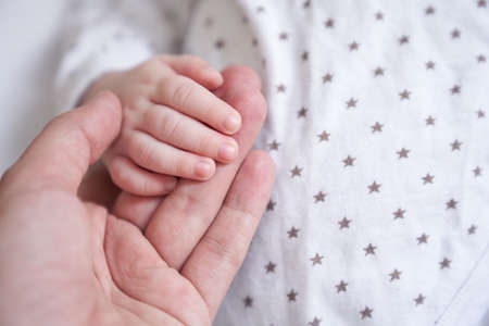 Mothers hand holding baby hand. The baby is one month old. Cute little hand with small fingers. Concept of love and care background. High quality photoの写真素材
