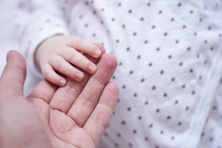 Mothers hand holding baby hand. The baby is one month old. Cute little hand with small fingers. Concept of love and care background. High quality photoの写真素材