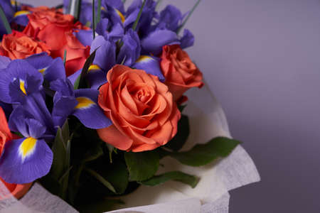 A colorful bouquet of flowers made of orange roses and purple irises. On a light background. A place to copy. The concept of the holiday. High quality photoの写真素材