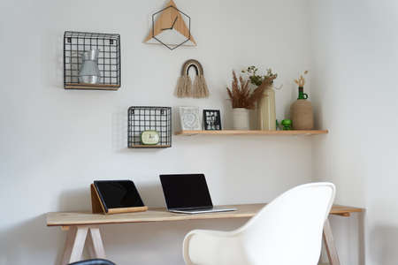 Stylish interior of the work area with a designer white table, chair, laptop and tablet on the...