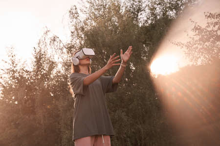 A girl wearing virtual reality glasses. He holds out his hands to the beam of sunlight. High quality...