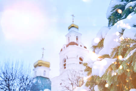 The gilded upper part of the Orthodox Christian church, against the background of the blue sky and snow-covered fir branches. Christmas background. Space for copying. High quality photoの写真素材