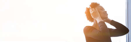 Banner An African-American woman listens to music with headphones. A young woman in a sports uniform on the background of a window. High quality photoの写真素材