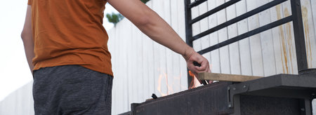 A mans hand holds a square barbecue grill, over the fire. The concept of preparing for a barbecue....