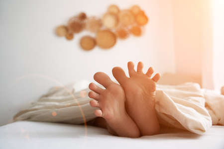 Close-up of a childs feet lying in bed in the morning, in the sunlight. High quality photo