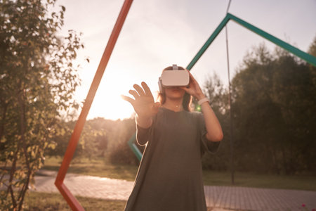 Close-up of a girl holding virtual reality glasses on her head with her hands, standing on a...