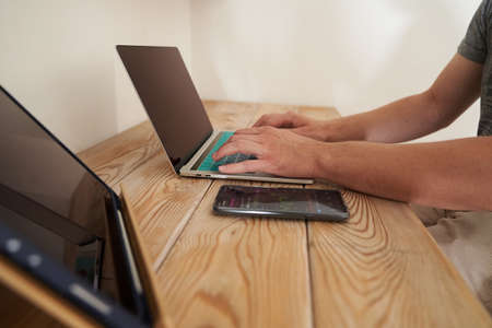 Close-up of a mans hands typing on a keyboard, looking for information. A freelance copywriter is...