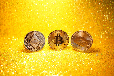 Three litcoin coins, ether. Litcoin and ether cryptocurrencies are the coin of the future. Golden shiny background. High quality photoの写真素材