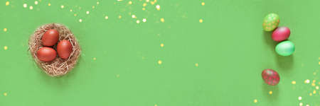 Banner with Easter eggs in a nest on a green background. Minimal concept. Top view. With a space to copy. High quality photoの写真素材
