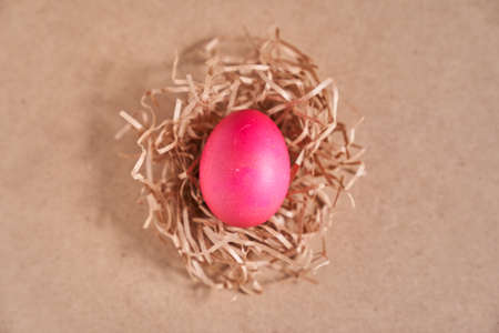 Top view, an Easter egg in a nest on a beige background. Minimal concept. With space to copy. High quality photoの写真素材