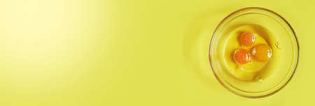 Banner.Three raw eggs on a yellow background with a space to copy. Breakfast preparation concept....