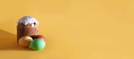 Banner colored Easter eggs on the background of Easter cake. Yellow background with space to copy. High quality photoの写真素材