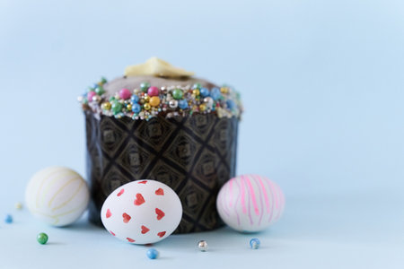 Close-up of three white Easter eggs with a pattern and one cake on a blue background. Orthodox...