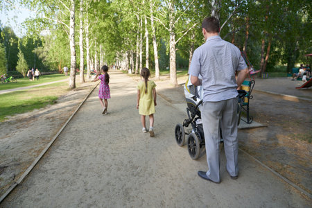 A family with a stroller walking in the park on a summer day, a family on the weekend. A happy...