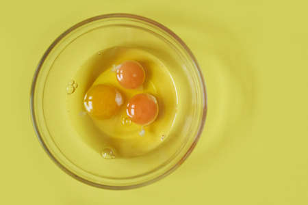 Three raw eggs on a yellow background with a space to copy. Healthy food. Fashionable color. High...