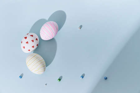 Close-up of three Easter eggs with a pattern of hearts and lines on a blue background. A shadow in...