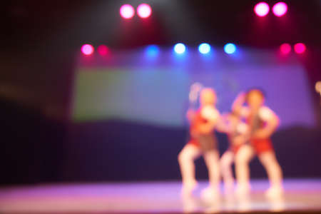 A colored blurry background of a dance festival from a group of little girls. Bright stage lighting....