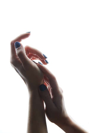 Graceful hands of a Caucasian girl on a white background. The manicure is blue.A womans hand with a beautiful colorful manicure. Fashionable bright colors. High quality photoの写真素材