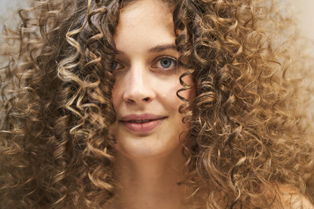 A beautiful portrait of a Caucasian woman with clean healthy skin and afro curls. Womens natural...