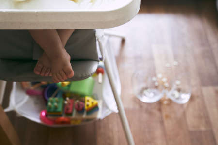 In the foreground are baby legs in a high chair.There is a broken transparent plate in the background. The concept of kitchen accidents is dangerous for young children. High quality photoの写真素材