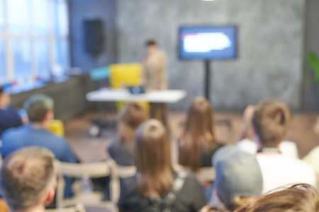 Blurred background of the business conference, one man on the stage, presentation of the project, public talk. Dark background. Copy space. Audience on the event, group of people on the training.の写真素材