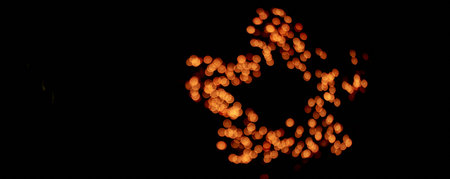 Banner. Isolated black background, blurred bokeh salute with warm golden lights in the shape of a...