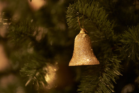 Selective focus. The branch of the Christmas tree is decorated with golden bell toys. The concept of decorating a Christmas tree for the new year. Overlay for your design. High quality photoの写真素材