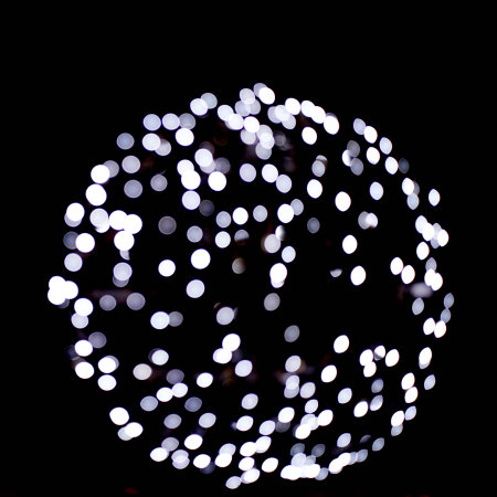 Close-up isolated black background of blurred bokeh with cold silver lights in the shape of a...