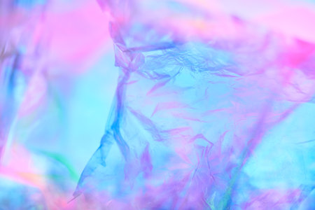 Transparent holographic wrinkled polyethylene background. Holographic colorful plastic film in blue,...