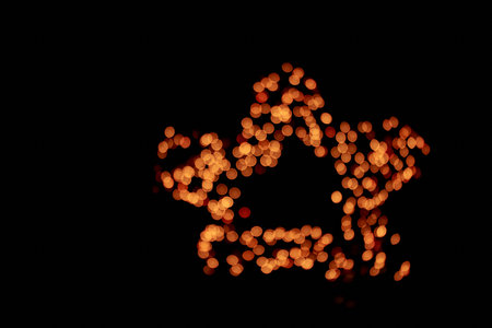 Isolated black background, blurred bokeh fireworks with warm golden lights in the shape of a star....
