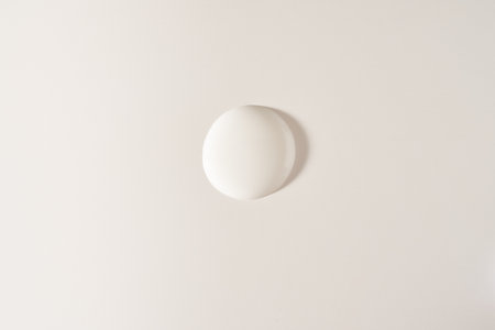 A round drop of cosmetic cream. A white creamy drop of skin care cream. A smooth drop isolated on a...