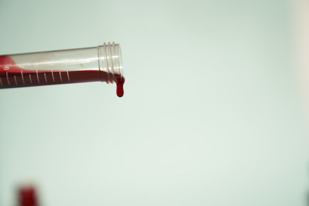 A transparent test tube for tests at an angle with red blood on a light background. Selective focus. With a space to copy. High quality photoの写真素材