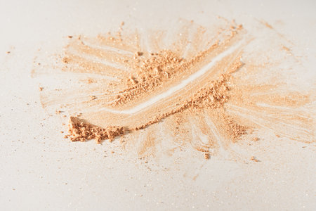 A smear of face powder, on a white background. Minimalistic modern cosmetic scene of bronzer or shadows, top view with space to copy. High quality photoの写真素材