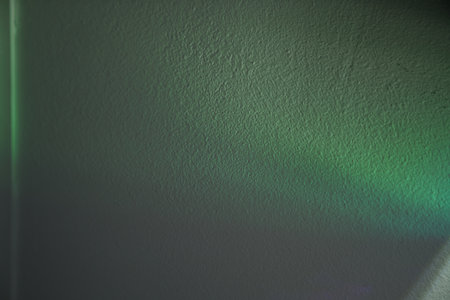 Green lights through the foil. Holographic abstract background in green tones. Lights on the wall with copy space. High quality photoの写真素材
