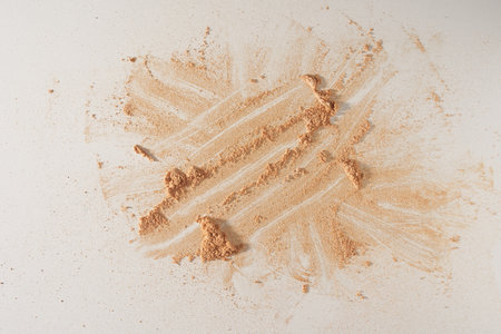 A smear of face powder, on a white background. Minimalistic modern cosmetic scene of bronzer or shadows, top view with space to copy. High quality photoの写真素材