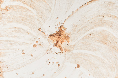 A neutral-colored face powder smeared on the surface, on a light background. Top view, flat position. Copy space. Powder texture. The form of the plane. High quality photoの写真素材