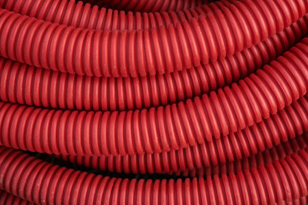 Corrugated for insulation cable of wires underground, plastic tube, electricity protection pipe for construction works, red corrugation close-up with copy space. High quality photoの写真素材