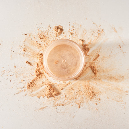 A neutral-colored face powder scattered on the surface in the form of a circle, pot on a light background. Top view, flat position. Mock up with gold powder and empty pot with space to copy.の写真素材