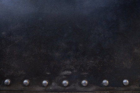 Metal rivets in a row on the scratched surface of the leather material. Overlay for your design with space to copy. High quality photoの写真素材