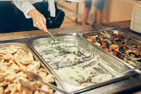 The teenager puts food on his plate. A steel tray with food in the schools self-service buffet. High quality photoの写真素材