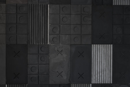 Textured black, gray geometric background made of concrete with stripes, squares, circles, crosses, tic-tac-toe, copy space. Concept of modern abstract creative wall design with bulky convex elements.の写真素材