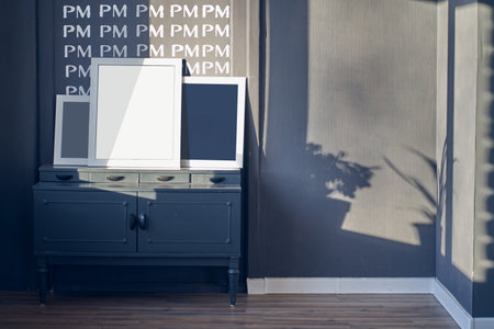 Interior design of dark grey room with TV stand, photo frames, shadow of plants, brown wooden floor....