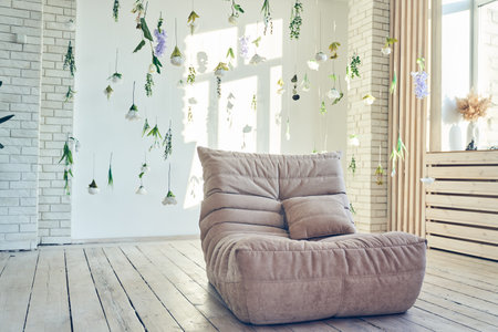 Interior design of room with soft sofa, artificial flowers levitating, hanging flowers on a white...