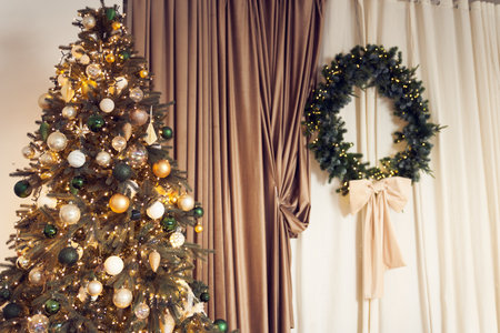 Close up of stylish interior in a classic style with Christmas trees and a wreath, bow, garland, string lights, brown and beige curtains, colorful balls. Background with copy space.の写真素材