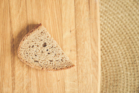 Top view of one slice of dark gluten-free rye bread against a wooden board with space to copy. High quality photoの写真素材