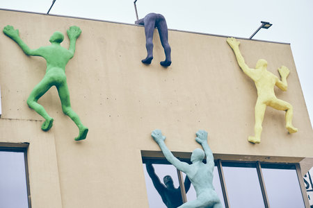 Great deals at the mall. The building is beige in color with an installation in the form of people climbing the wall. The concept of shopping, people are rushing to the sale. High quality photoの写真素材