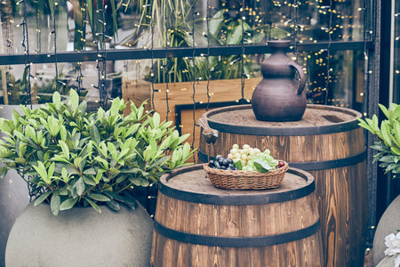 Decorative elements of open restaurants. In the foreground is a basket with grapes.A jug handmade by...